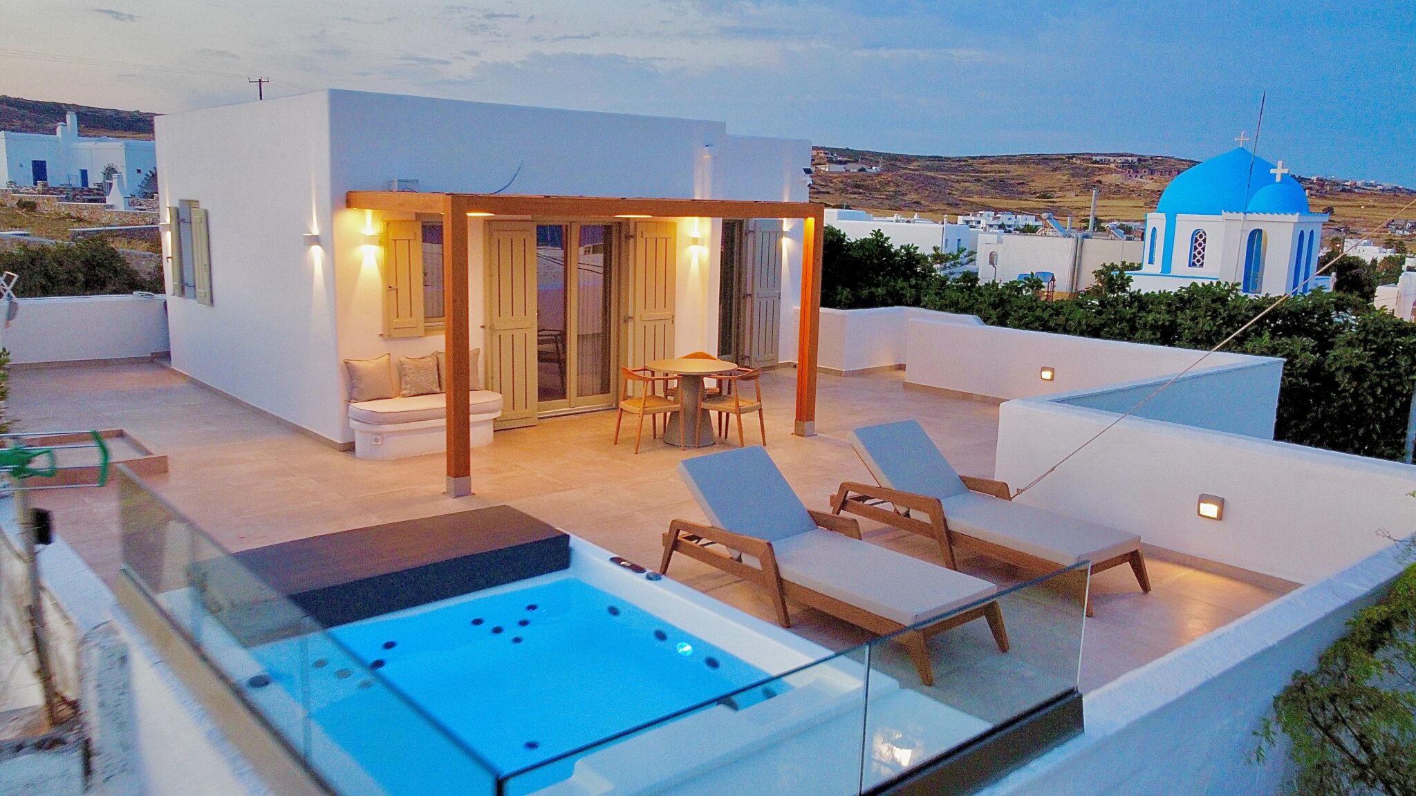 Suite with Jacuzzi – terrace with pergola, dining table and heated jacuzzi, evening light